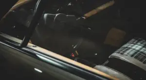 Dark car interior with steering wheel and plaid seat fabric, illustrating deodorizing a vehicle's interior.