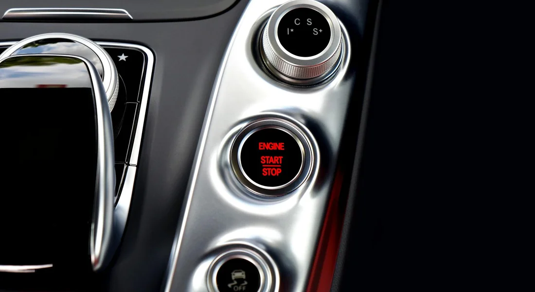Close-up of a modern car dashboard with the engine start/stop button and climate controls, highlighting the HVAC area.
