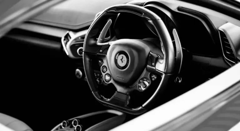 Black-and-white close-up of a car's interior steering wheel and dashboard