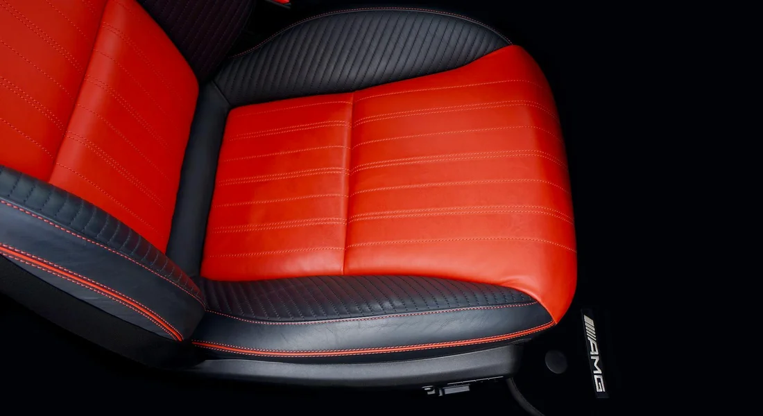 Close-up of a red and black leather car seat featuring AMG branding, illustrating the focus on safety during cleaning.