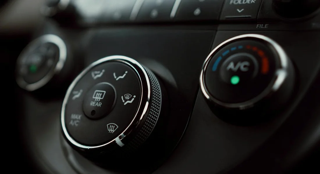 Close-up of a car's climate control knobs, including the air conditioning and vent dials.