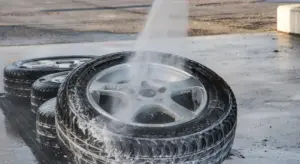A car wheel being rinsed with water spray and soap suds around the tire at a car wash.