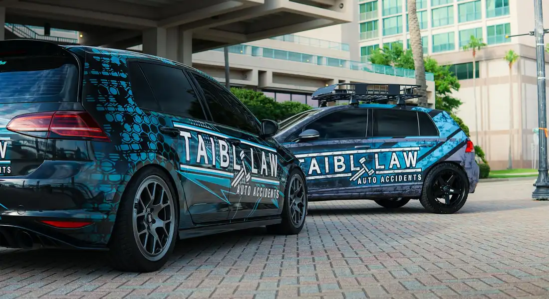 Two blue camouflage vinyl-wrapped cars parked near a building, illustrating different vehicle wrap materials.