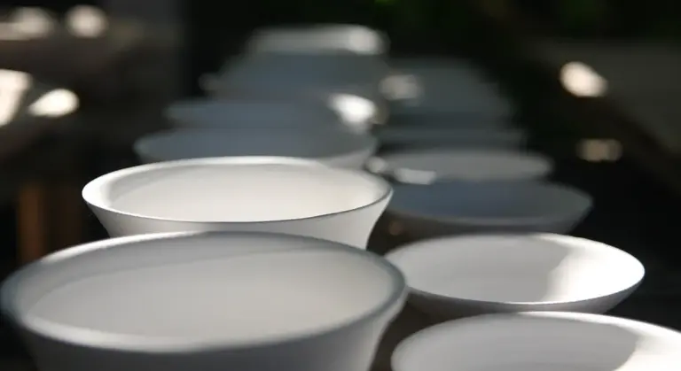 Close-up of white ceramic cups lined up with shallow depth of field.