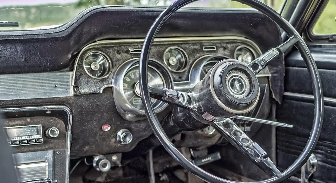 Close-up of a vintage car dashboard and large steering wheel