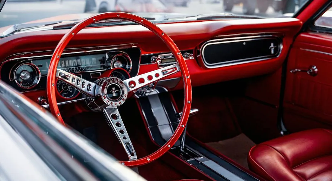 Red vintage car interior with a chrome-spoked steering wheel and red leather seats