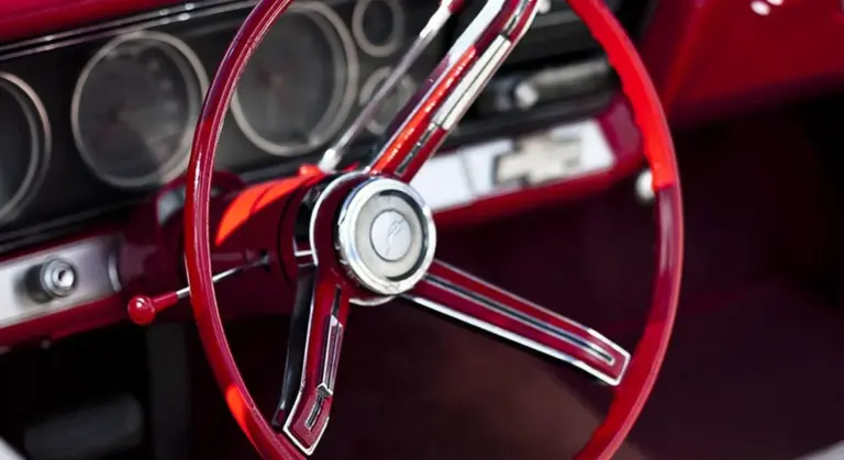 Close-up of a red vintage car steering wheel inside a classic car interior