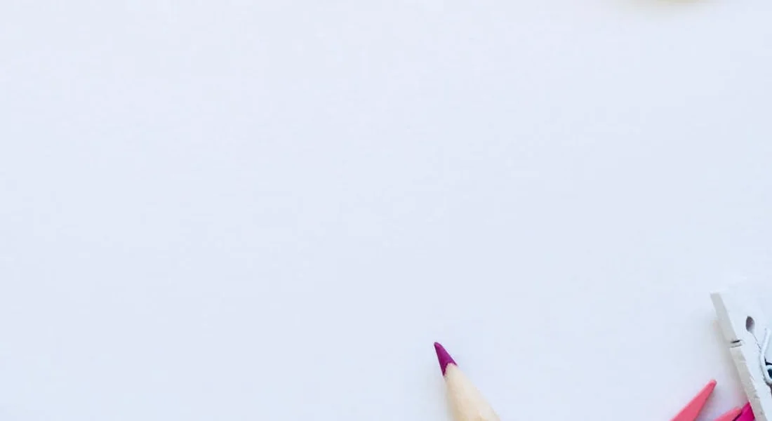 Close-up of a pale-yellow pencil with a pink tip on a white surface, with small drafting tools visible in the corner, suggesting planning and marking before masking in car detailing.