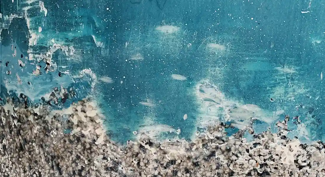Close-up of turquoise car bumper paint with visible cracks and chipped, rough edges along the bottom.