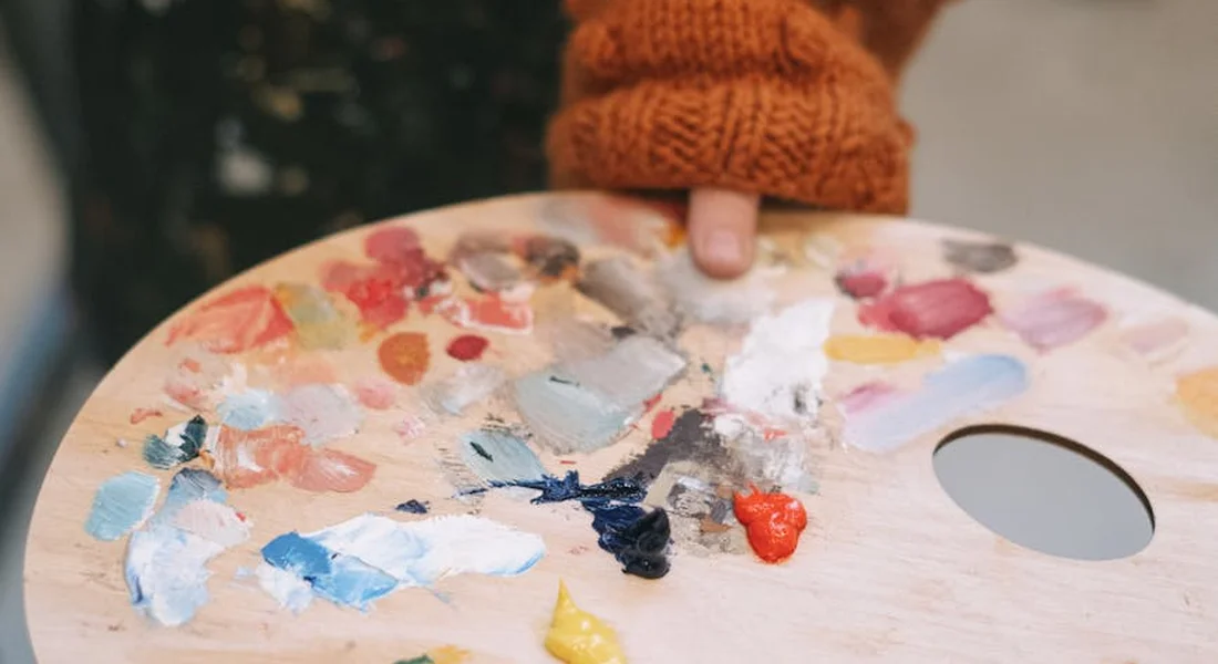 Painter’s palette with mixed automotive paints and a gloved hand, illustrating color matching for touch-up work.