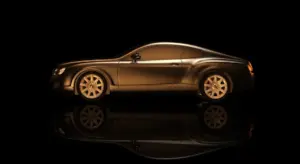 Side profile of a sleek gold-brown car with a glossy reflection on a black background