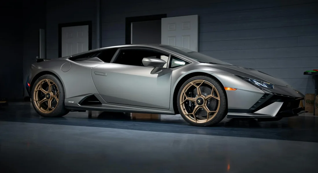 Gray sports car with bronze alloy wheels in a dark garage