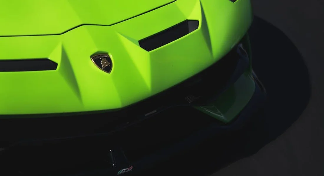 Close-up of a neon green car bumper with angular lines and a shield-shaped badge.