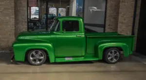 Bright green vintage pickup truck with chrome wheels in a showroom