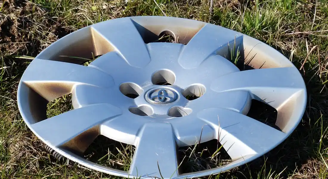 A silver car hubcap lying on green grass.