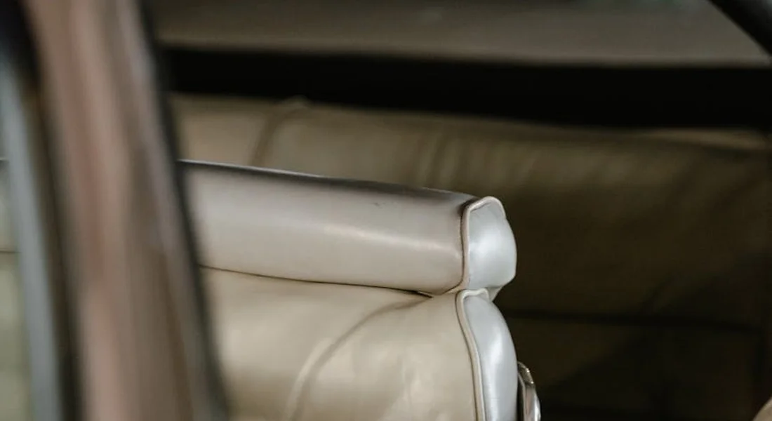 Close-up of beige leather car seat with stitching and a small scratch along the seam
