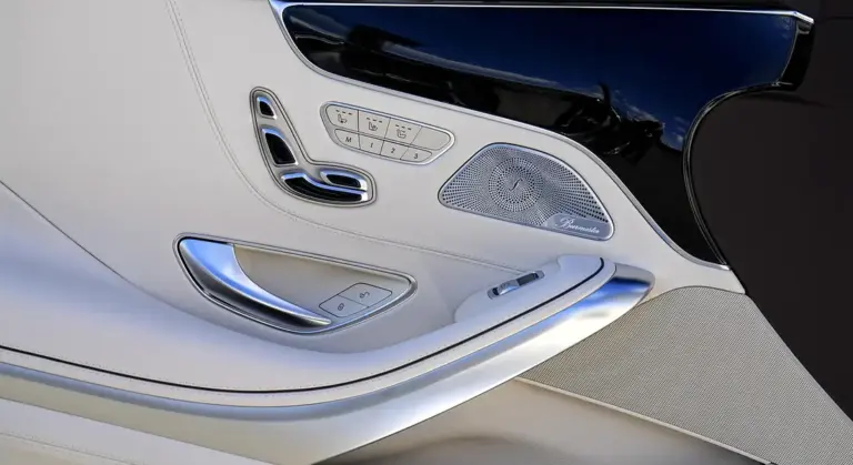 Close-up of a luxury car's white leather interior door panel with control buttons and a speaker.
