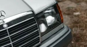 Close-up of a car's front end showing the headlight, grille, and plastic trim