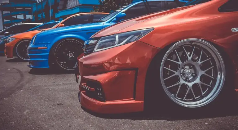 Close-up of several colorful car bumpers in a row, showcasing glossy red, blue, and orange finishes.