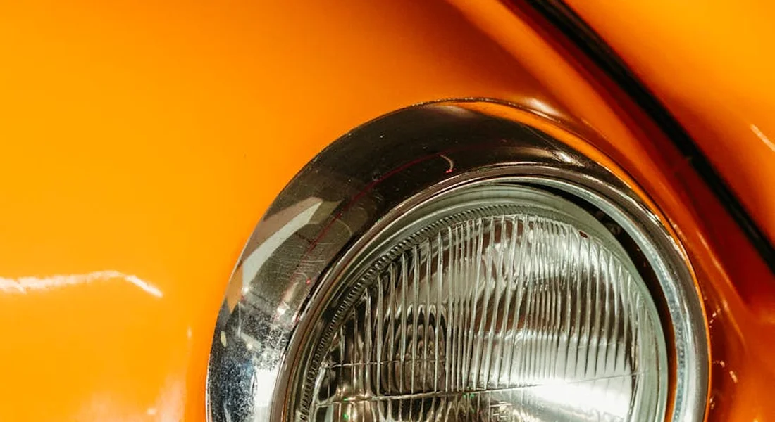 Close-up of an orange car's headlight and surrounding bodywork