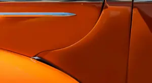 Close-up of an orange car door panel with a glossy finish and visible panel seam.