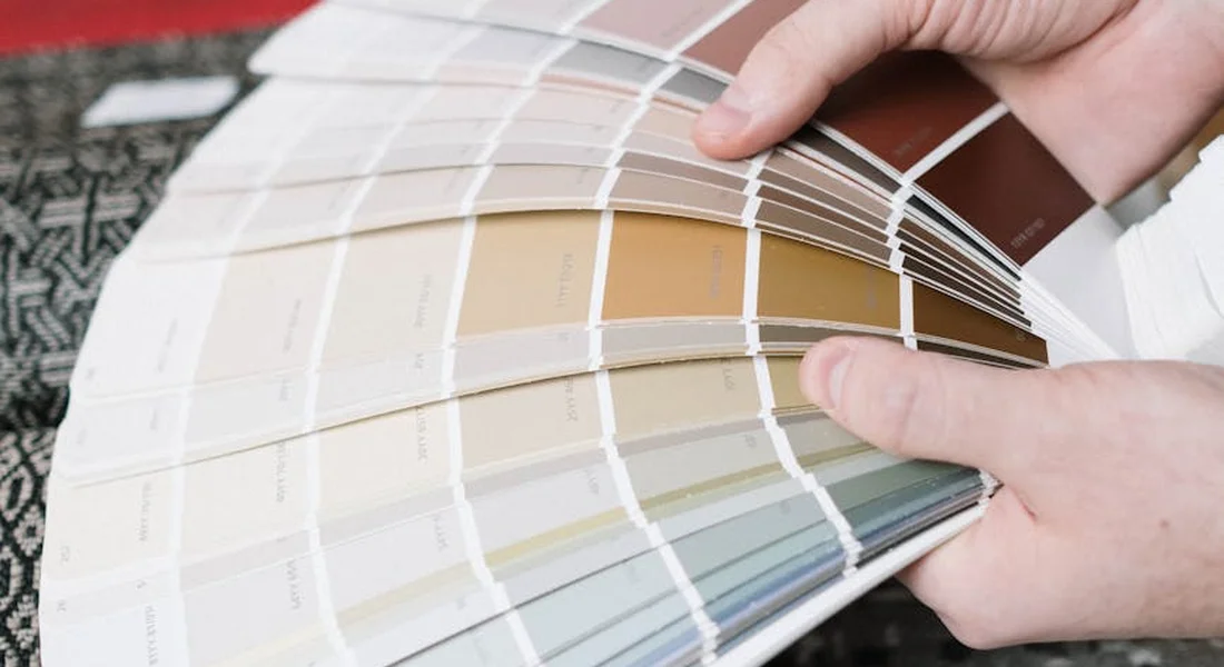 Hands holding a fan of paint color swatches to match car paint for rock chips