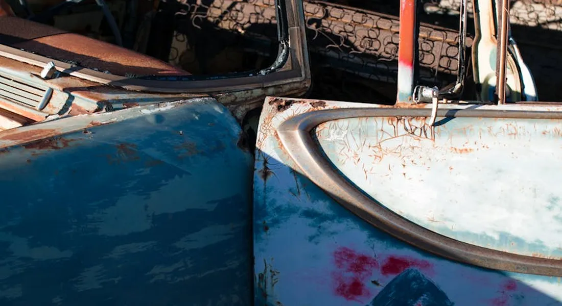 Close-up of a vintage blue car door with paint transfer, scrapes, and chipped paint.