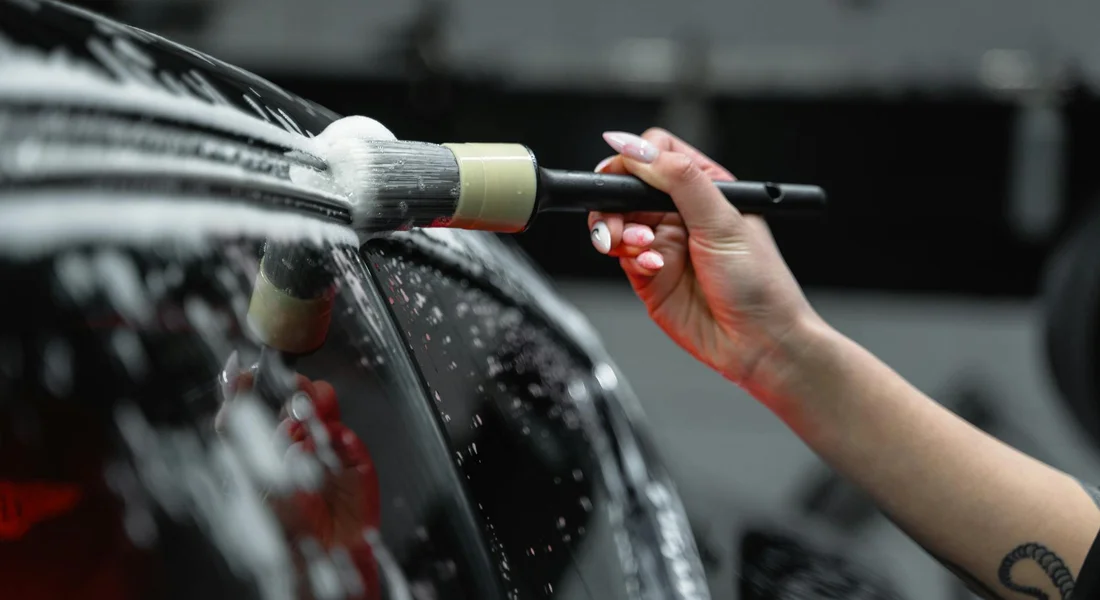 Close-up of a technician using a mechanical paint-stripping tool on a car panel