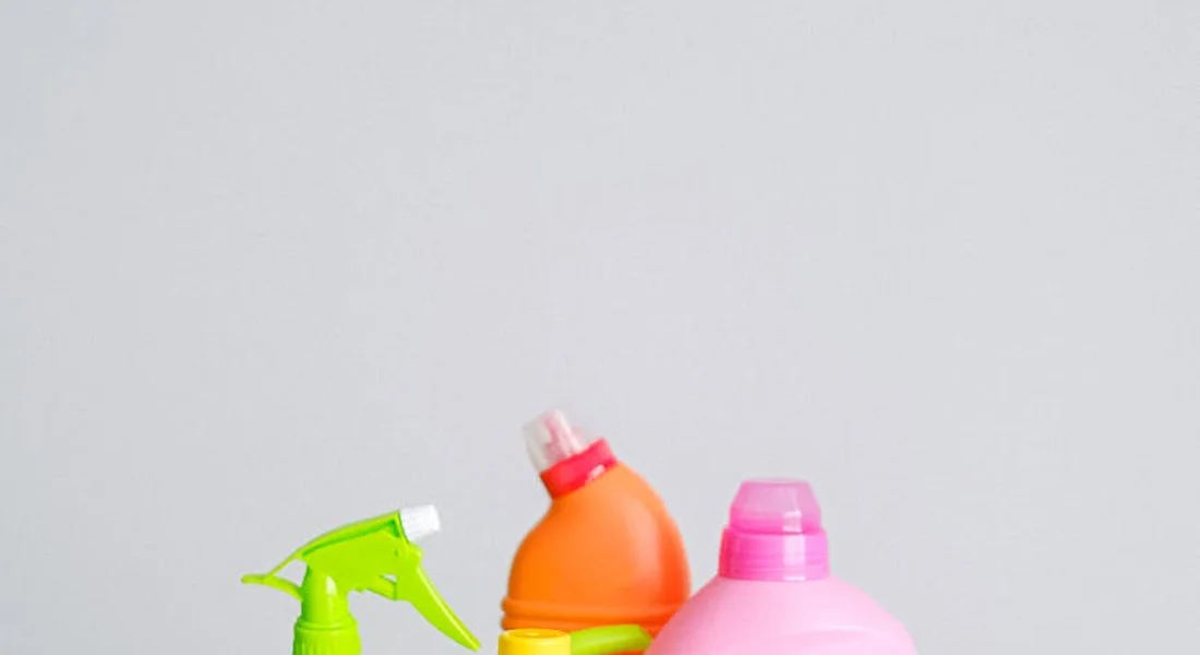 Assorted plastic spray bottles on a pale gray surface, representing cleaning tools for car interior and exterior trim.