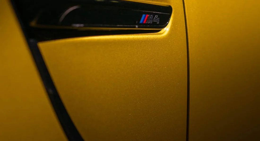 Close-up of a yellow BMW M4 door panel with metallic paint and a black trim piece.
