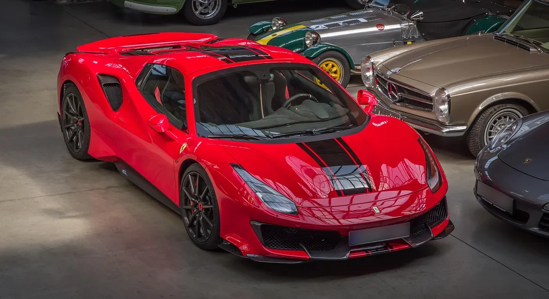 Red luxury sports car in a showroom with other classics, illustrating a professional vinyl wrap removal scenario