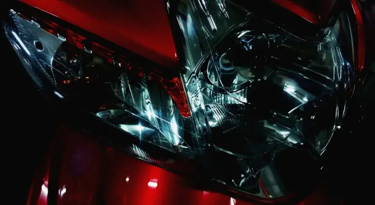 Close-up of a red car headlight assembly with a clear, reflective lens