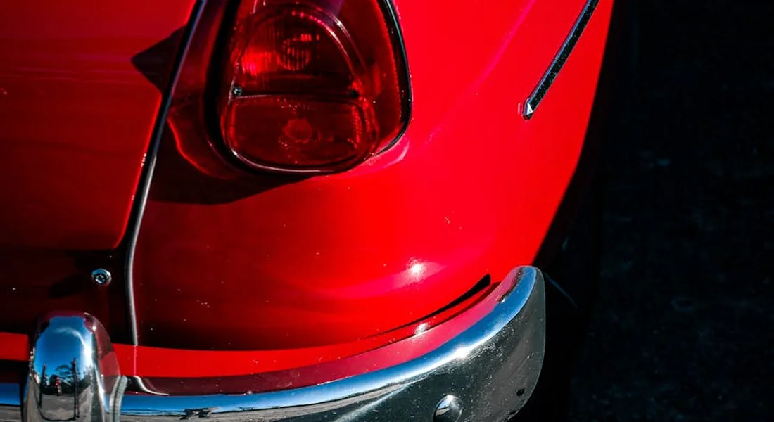 Close-up of a red car bumper with chrome bumper trim.
