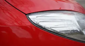Close-up of a red car showing glossy paint near the headlight.