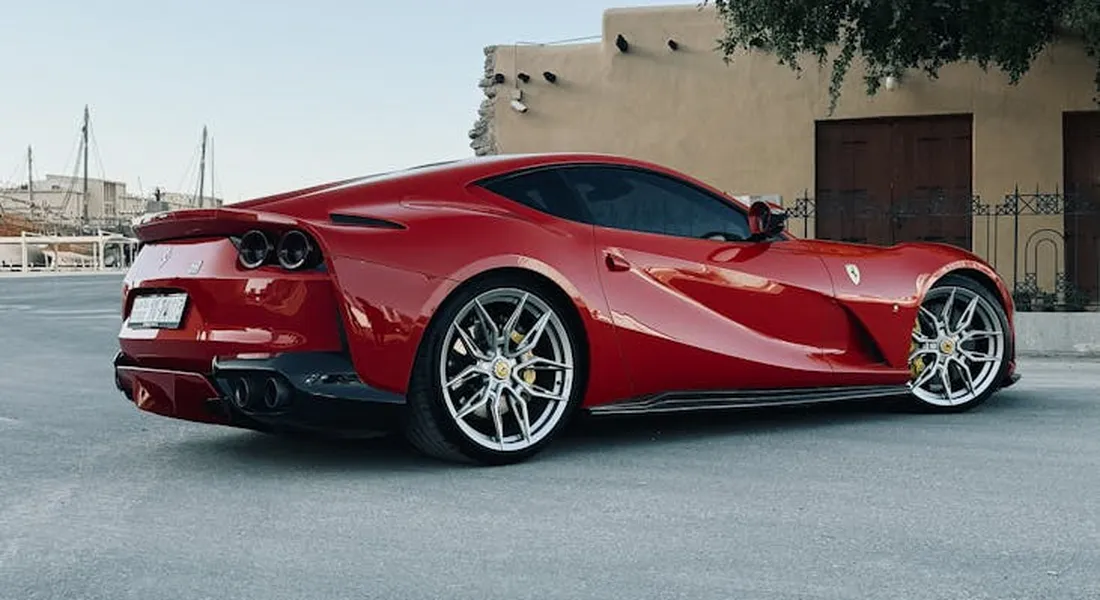 Red sports car parked on a street with a beige building in the background