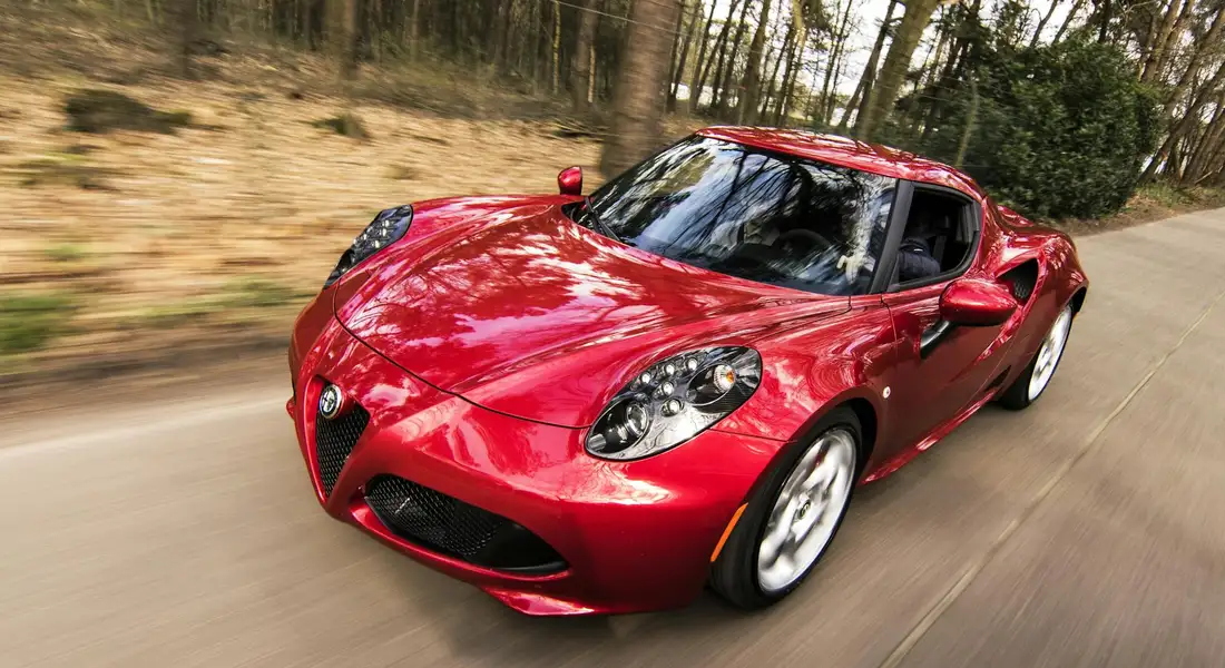 Red sports car in motion on a road, with a glossy finish highlighting its curves.