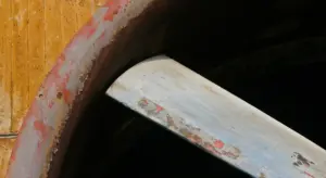 Close-up of a car body edge with chipped paint and visible rust spots near a curved panel.