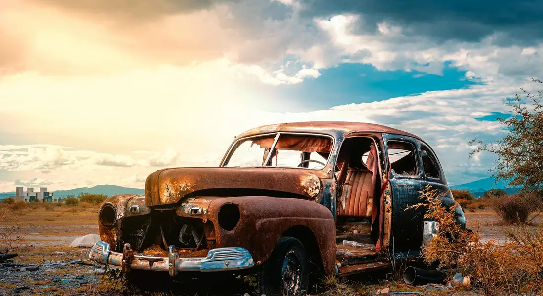 Rust-covered vintage car in a desolate desert landscape