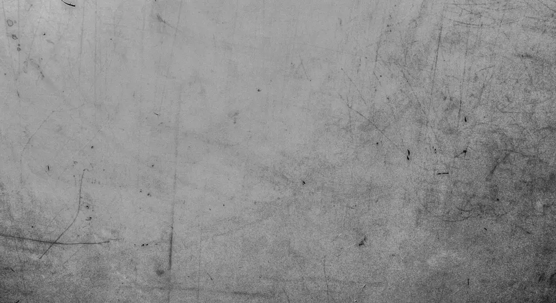 Close-up of a gray, scratched metal surface with visible scuffs and lines.