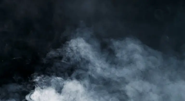 Dark background with white smoke or mist in the foreground, abstract scene