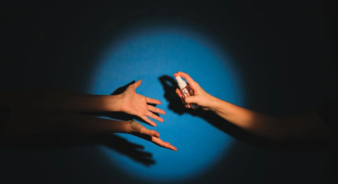 Two hands exchanging a spray can under a blue spotlight, illustrating preparation for spray painting.