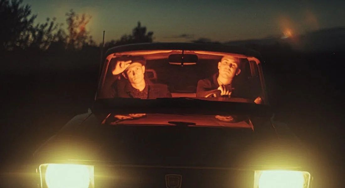 Two people in a car with bright headlights on in the dark, illustrating exterior headlight restoration