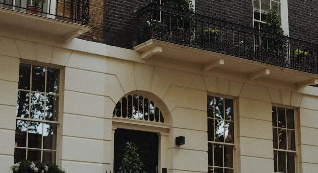 Facade of a light-colored townhouse with an arched doorway and large windows