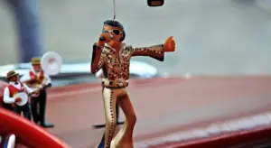 A small toy figurine on a car dashboard with a blurred background.