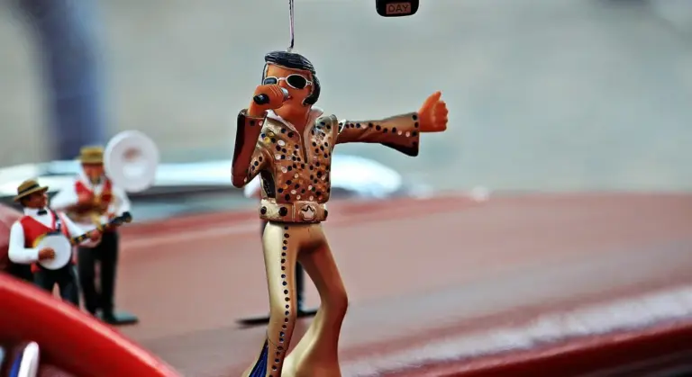 A small toy figurine on a car dashboard with a blurred background.
