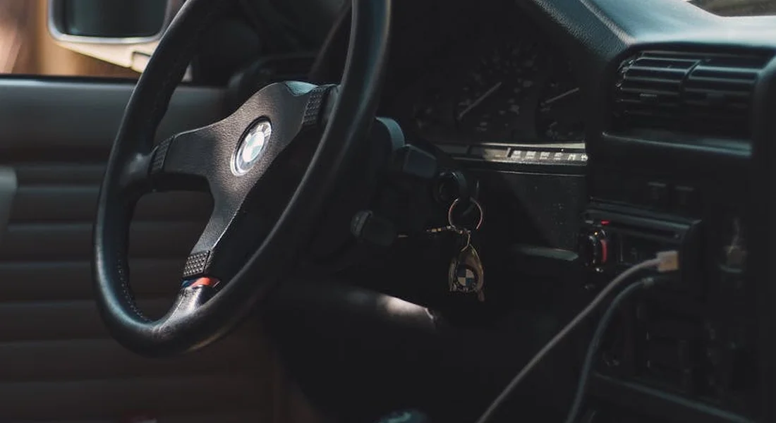 Interior of a car showing the steering wheel, dashboard, and keys as part of a diagnostic inspection for odor sources.