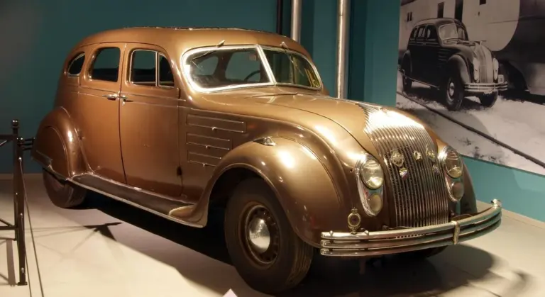 Classic brown vintage car on display with glass windows visible.