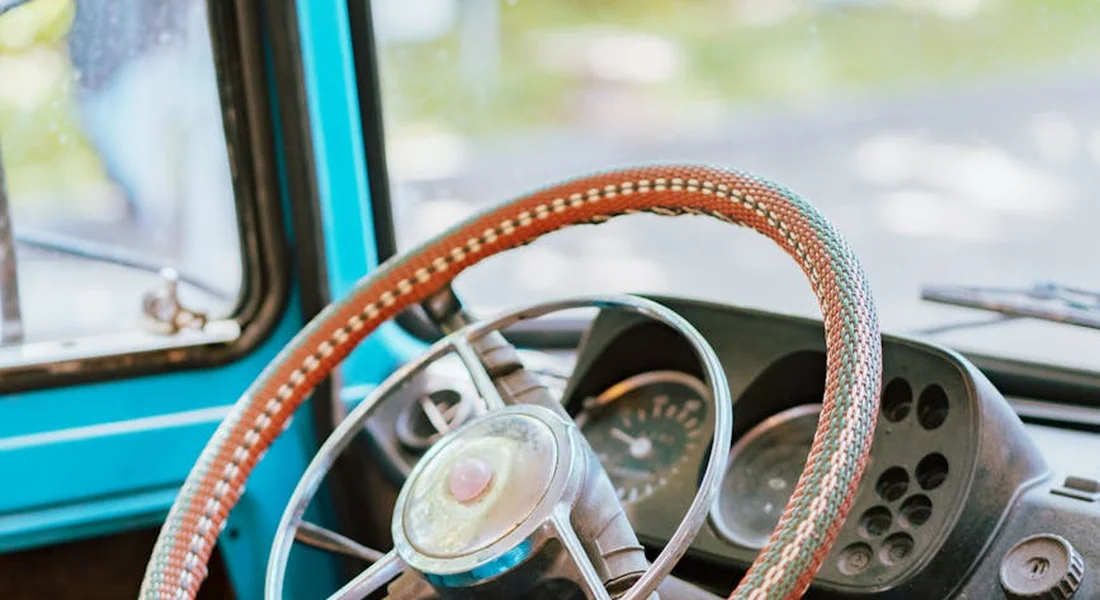 Close-up of a vintage blue car interior featuring a chrome steering wheel and dashboard, illustrating a vehicle setting for a discussion on acrylic paint on car windows.