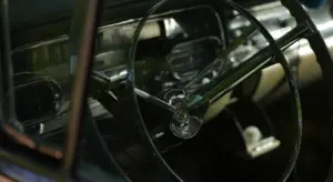 Close-up of a vintage car interior with a chrome steering wheel and classic dashboard.