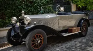 Antique open-top car from the early 20th century parked on a cobblestone street.